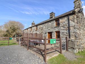 an old stone house with a wooden bench in front of it at Cwm Yr Afon Cottage in Harlech