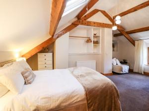 1 dormitorio con cama blanca grande y techo de madera en Cwm Yr Afon Cottage, en Harlech
