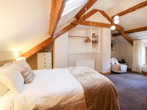 a bedroom with a large white bed and wooden ceilings at Cwm Yr Afon Cottage in Harlech