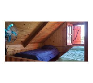 two beds in a wooden cabin with a fan at Hermosa Cabaña Con Pileta in Chivilcoy