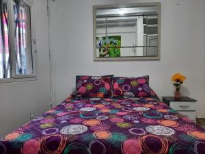 ein Bett mit farbenfroher Bettdecke in einem Schlafzimmer in der Unterkunft Espectacular apartamento primer piso capacidad 6 personas in Villamaría