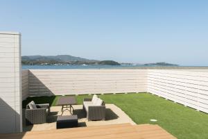 eine Terrasse mit 2 Stühlen, einem Tisch und Gras in der Unterkunft 淡路島貸別荘リアンみなと in Minamiawaji