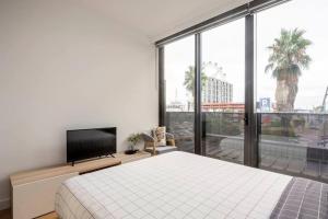 1 dormitorio con 1 cama y TV de pantalla plana en Centrally Located Modern Loft w Free Parking, Infinity Pool, Workspace en Melbourne