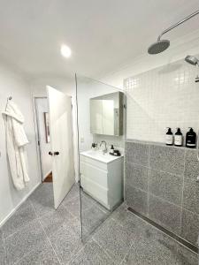 W łazience znajduje się prysznic, umywalka i lustro. w obiekcie Guest house on the park w mieście Burwood East