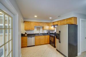 a kitchen with wooden cabinets and a refrigerator at Gulfport Condo with Private Balcony - Walk to Beach! in Gulfport
