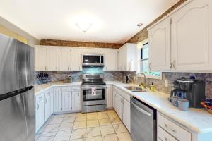 a kitchen with white cabinets and a stainless steel refrigerator at Valley Retreat - Upper in Holiday Island