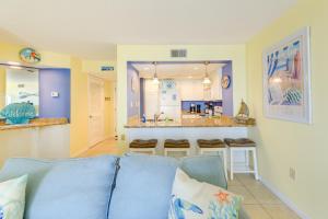 uma sala de estar com um sofá azul e uma cozinha em North Carolina Escape with Balcony and Pool Access! em North Topsail Beach