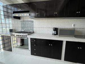 a kitchen with black cabinets and a stove at Deco 3 Downtown 3 bed Apartment in Cancún +8 photos