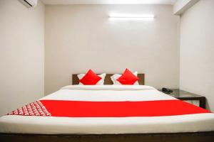 a red and white bed with red pillows on it at Flagship Hotel Joy in Jaipur