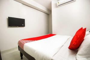 a bedroom with a bed with red pillows and a tv at Flagship Hotel Joy in Jaipur