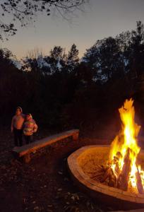 a fire pit with two people standing next to it at Pinar del Valle - Glamping en el Bosque - Propiedad Completa en Constanza in Constanza