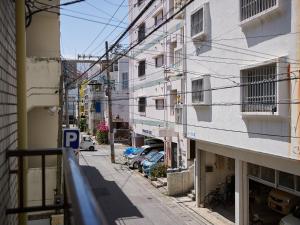 那霸的住宿－Guest house II Rokumarukan，一条有建筑的小巷和一条有汽车的街道