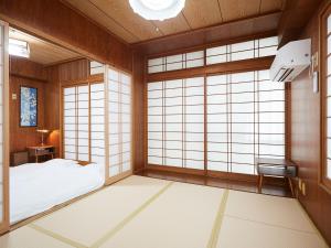 a japanese room with a bed and windows at Guest house II Rokumarukan in Naha
