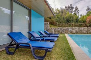 een rij blauwe ligstoelen naast een zwembad bij Casa do Poço in Caminha