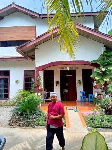 a man standing in front of a house at ORANGUTAN TREKKING LODGE Jungle Tour Only Book with Us in Bukit Lawang