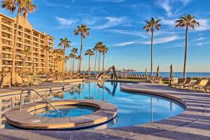 a resort with a swimming pool and palm trees at Sandy Beach Sonoran Spa W504 Ocean Front Resort in Puerto Peñasco