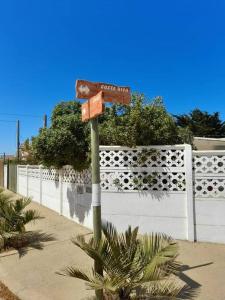 um sinal de rua em frente a uma cerca branca em Agradable casa al lado de la playa em Las Cruces