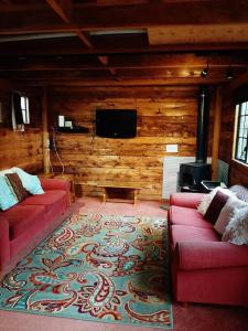 sala de estar con 2 sofás rojos y TV de pantalla plana. en Willowbrook, en Ohakune