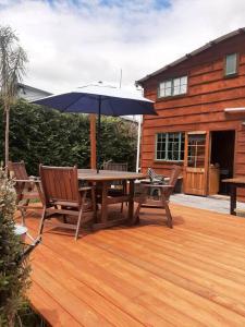a wooden table and chairs with an umbrella on a deck at Willowbrook in Ohakune