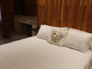 a bed with white sheets and pillows with a fireplace at Fazenda Capuava in Bananal