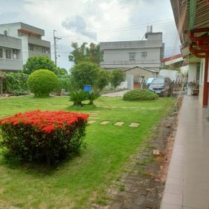 um jardim verde com flores vermelhas e um passeio em J ancient house em Lucao