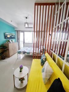 ein Wohnzimmer mit einem gelben Sofa und einem Bett in der Unterkunft Stylish New Unit w/ Balcony at Fern Residences in Manila