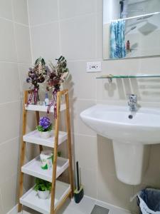 ein Badezimmer mit einem Waschbecken und einem Regal mit Blumen in der Unterkunft Stylish New Unit w/ Balcony at Fern Residences in Manila