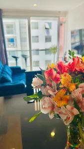 un jarrón lleno de flores sentado en una mesa en Casa Sol Apartamento vista al mar cerca del aeropuerto y Miraflores en Lima