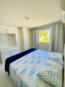 a bedroom with a blue and white bed with a window at Apartamento encantador térreo em condomínio fechad in Porto De Galinhas
