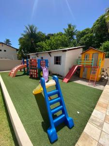 um parque infantil com um escorrega e uma estrutura de jogos em Apartamento encantador térreo em condomínio fechad em Porto de Galinhas