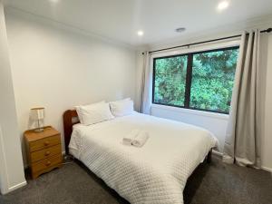 um quarto com uma cama branca e uma janela em NO PARTY ALLOWED, Entire Brand New 3 bedroom townhouse, free unlimited fibre wifi and free parking em Wellington