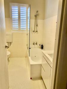a white bathroom with a tub and a sink at Wellington Bondi Beach in Sydney