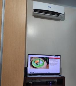 a computer monitor on a desk with a air conditioner at Cozy Studio Unit near Uptown Mall BGC in Manila
