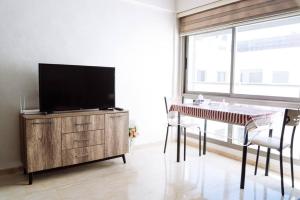 a living room with a tv on a dresser and a table with chairs at Cozy New Studio in Mohammedia in Mohammedia