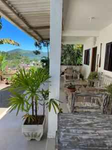 een veranda met tafels en stoelen en een plant bij Vista pro mar in Ubatuba