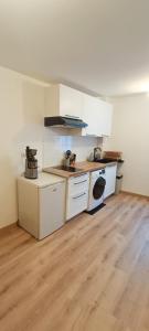 a kitchen with white cabinets and a wooden floor at Élégant et central in Perpignan