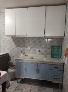 uma cozinha com um lavatório e armários brancos em Casa Penedo em Itatiaia