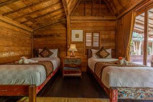 two beds in a room with wooden walls at Jukung Cottage in Nusa Penida