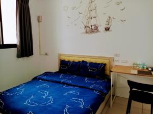 礁溪鄉的住宿－漁海民宿，一间卧室配有一张带蓝色床单的床和一张书桌。