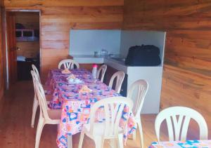 a dining room with a table and chairs and a kitchen at Cozy cabin Casa Enya in Sibundoy