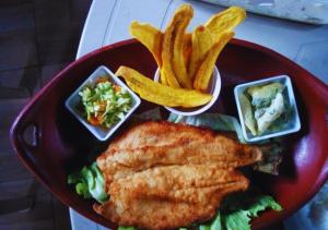 un plato rojo de comida con pescado y patatas fritas y verduras en Cozy cabin Casa Enya, en Sibundoy