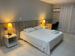 1 dormitorio con 1 cama blanca grande y 2 lámparas en Aquarius Flat Studio 509 en Santa Cruz do Sul