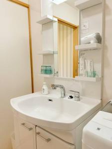 uma casa de banho com um lavatório branco e um espelho. em 北部観光アクセス良好な新築貸別荘／最大4名ベッド4台／Wi-Fi／海岸線近く em Nago