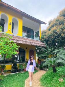 una mujer caminando delante de una casa amarilla en Ostrich homestay - Venue Travel, en Ba Vì
