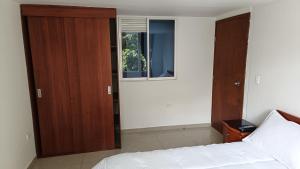 a bedroom with a white bed and a window at Edificio El Trébol in Bogotá