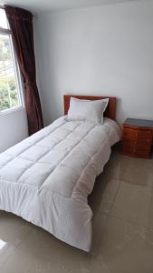 1 cama blanca grande en un dormitorio con ventana en Edificio El Trébol, en Bogotá