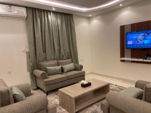 een woonkamer met 2 banken en een flatscreen-tv bij شقق سويت ستار الفندقية in Tabuk