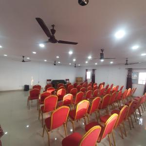 Cette grande chambre dispose de chaises rouges et d'un ventilateur de plafond. dans l'établissement Hotel Daisy Park, à Siddharthanagar