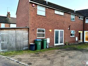 a brick house with two trash cans and a fence at Central Semi - Detached Home with Private Parking! in Buckinghamshire