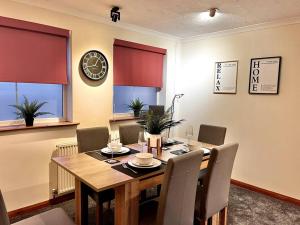 a dining room table with chairs and a clock on the wall at Central Semi - Detached Home with Private Parking! in Buckinghamshire